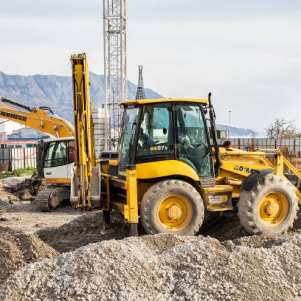 Budva, Montenegro, February 05, 2019: Construction work on the construction site of the city. Excavator digs a pit, a worker is directing the work