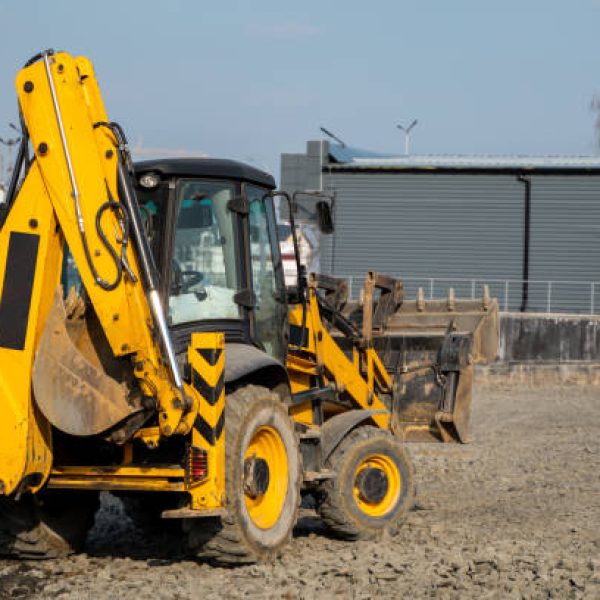 Yellow wheel loader Excavator machine working at construction site with a sand and gravel. Preparing of the fundament for a asphalting. Road construction site. Building of a parking